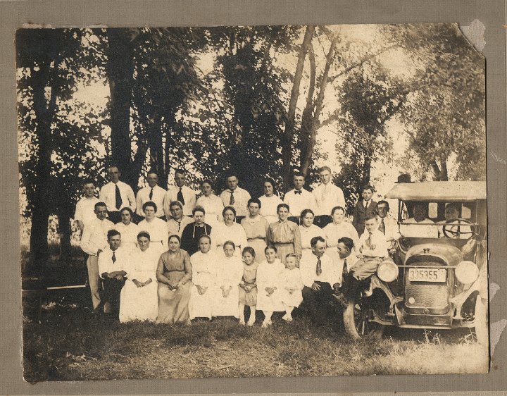 0023.jpg - front:  Jay [Jason] Yoder, Barbara Yoder Martin, Alice S. Brenneman, Louisa S. Gingerich, Katie S. Brenneman, Grace S. Rhodes, Ollie S. Blosser, Mary S. Stutzman [?], Nicholas Yoder, Lloyd Swartzendruber [?] head turned, Willard S., sitting on bumper [Cat Preacher], Emory Yoder [passenger seat], Frank S. [Driver seat, owner] cripple, always drove up front.  Middle Row:  Orval S., Carrie S., Lovina Gingerich [Viney], Nora Gingerich [?] mother of Lovina, Katie S. Reschly, Ruth Schrock, ??? [Eicher], Mamie A, Ethel Bender, Ida Schrock, Harvey S. [not the uncle, but the cousin, next to car].  Back:  Rolla S., Eli Yoder, Jay Boller, Quinton Yoder, Carrie S., Lloyd Yoder, Sadie Yoder, Joe Erb [?], ??, ?? boy.  1920.